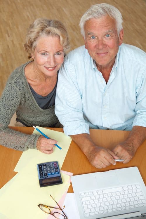 Senior couple reviewing retirement finances with a laptop and calculator