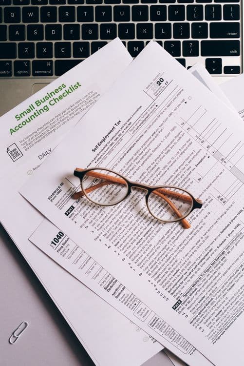Tax documents and eyeglasses on a laptop keyboard